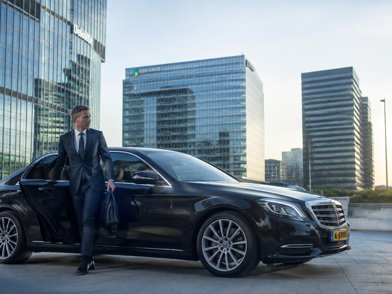 Zakenman stapt uit een Mercedes met chauffeur op de Zuidas